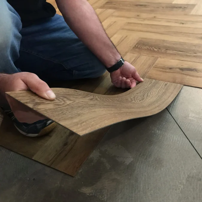 Installer fitting a click-lock LVT plank over an existing floor